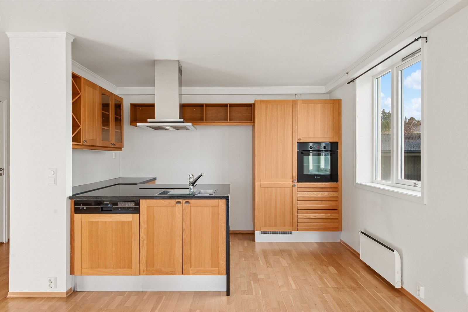 Kjøkkeninnredningen er stilren og tidløs, med brune, profilerte fronter og en solid benkeplate i granitt med nedfelt oppvaskkum i stål. Galleribilde