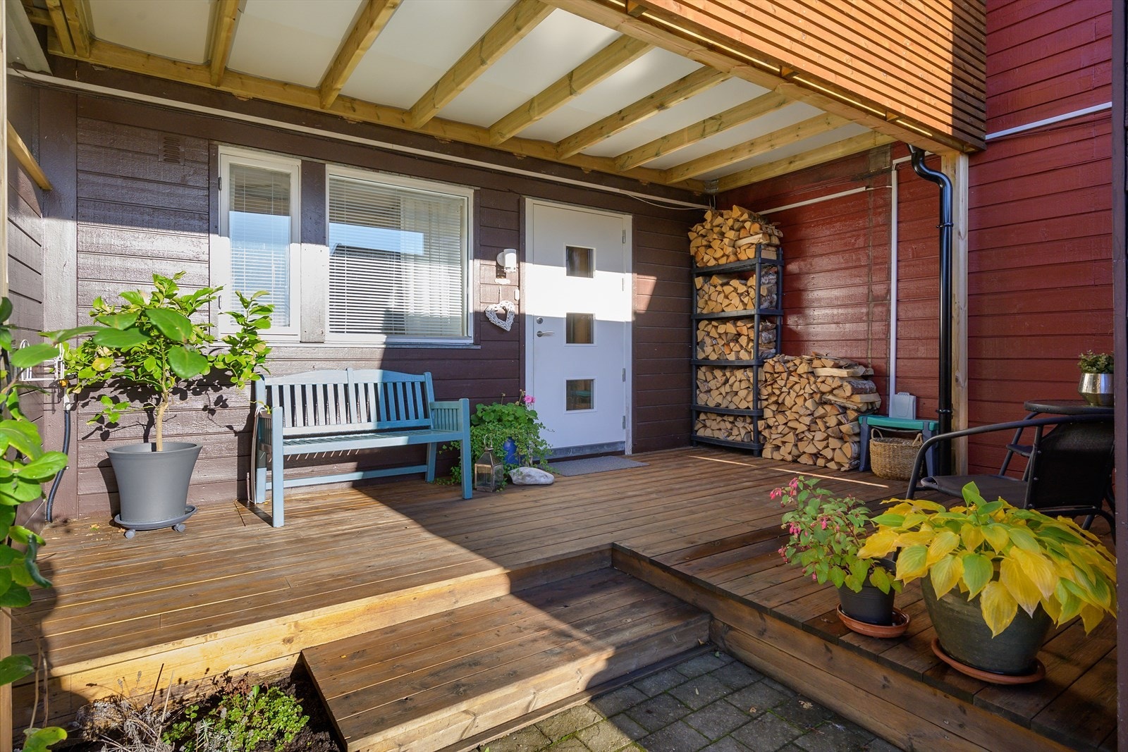 Inngangspartiet har et overbygg som gir ly for vær og vind. Plass til både benk, vedlagring og en liten sittegruppe som gjør sonen nyttig store deler av året. Galleribilde
