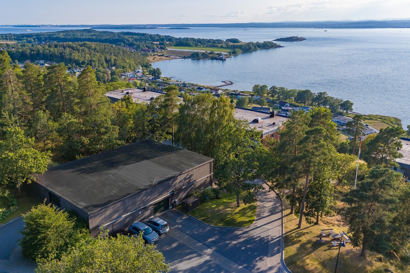 Fra parkering i garasje fører steinbelagte stikkveier og pent opparbeidede uteområder til inngangsparti. Det er enkel adkomst til leiligheten med to etasje ned. Galleribilde