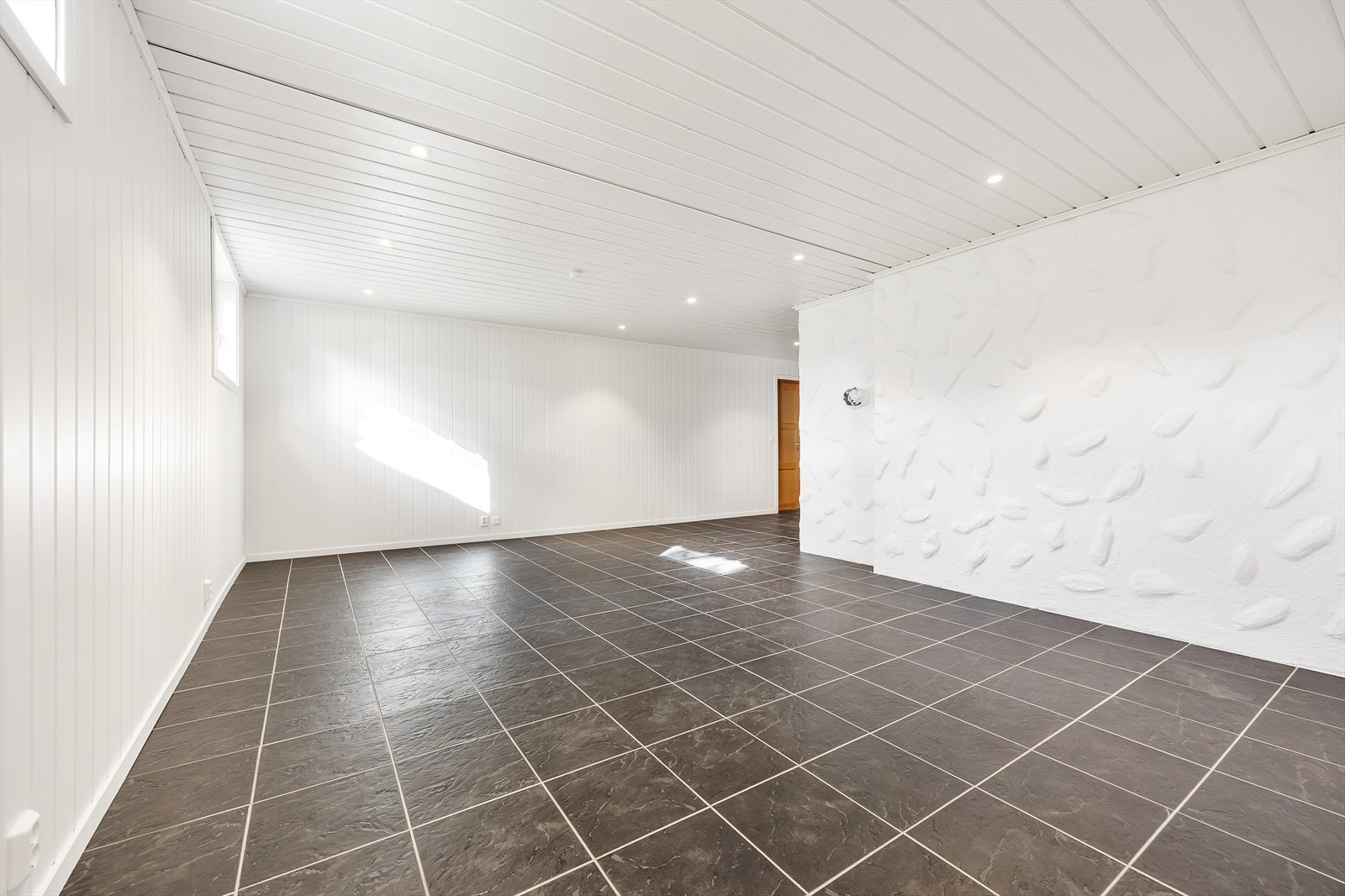 Vegger og tak er hvitmalt med downlights i himlingen, mens det på gulvet er koksgrå fliser med lun gulvvarme. Galleribilde