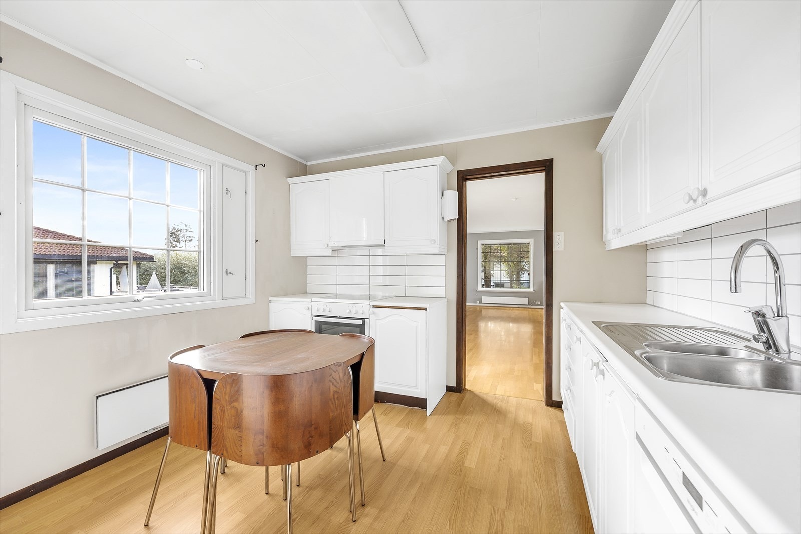 Innredningen har hvite, profilerte fronter og hvit laminatbenkeplate med nedfelt kum i stål. Galleribilde