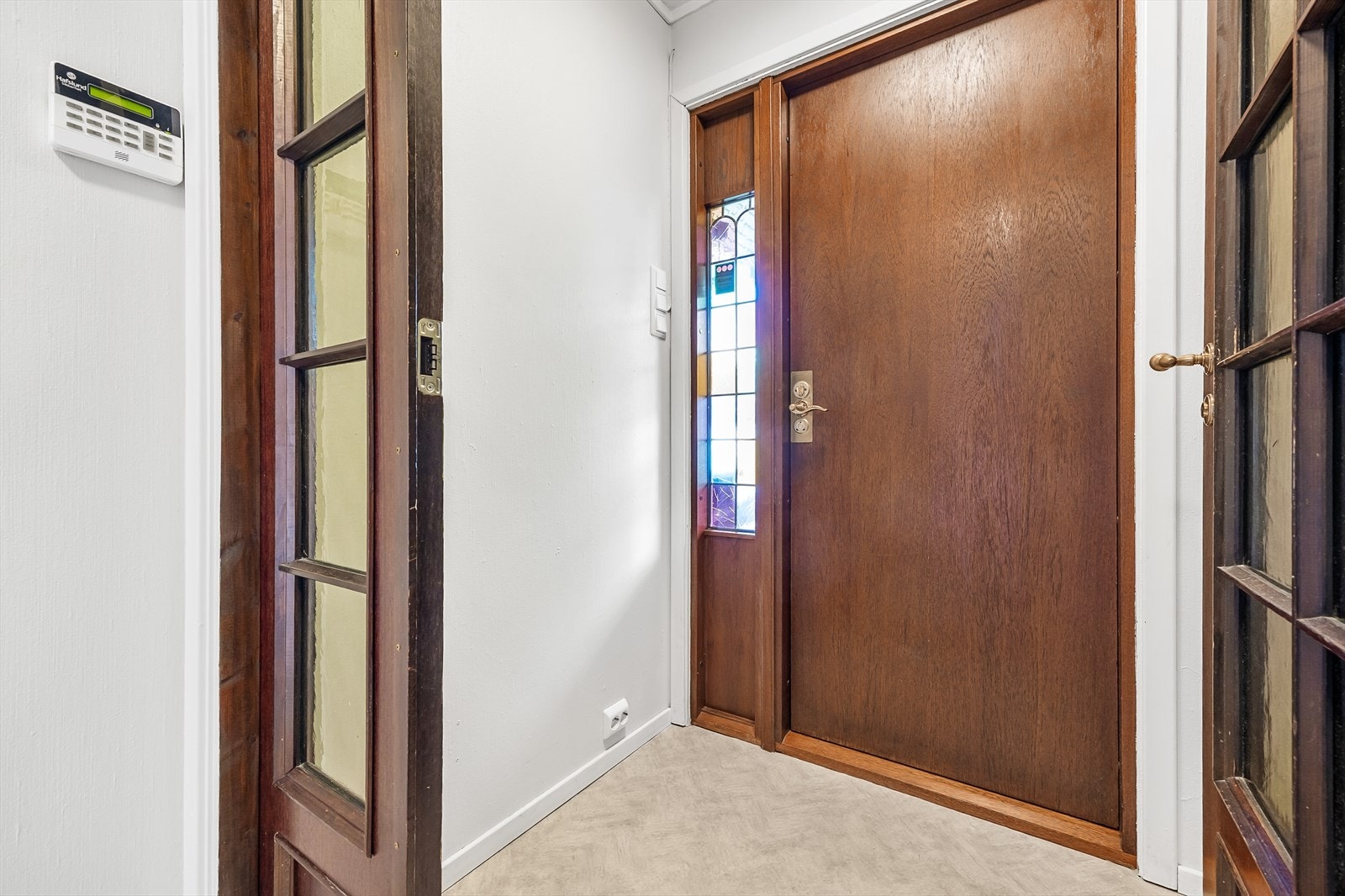 Entréen har hvitmalte veggflater og grått belegg på gulvet. Galleribilde