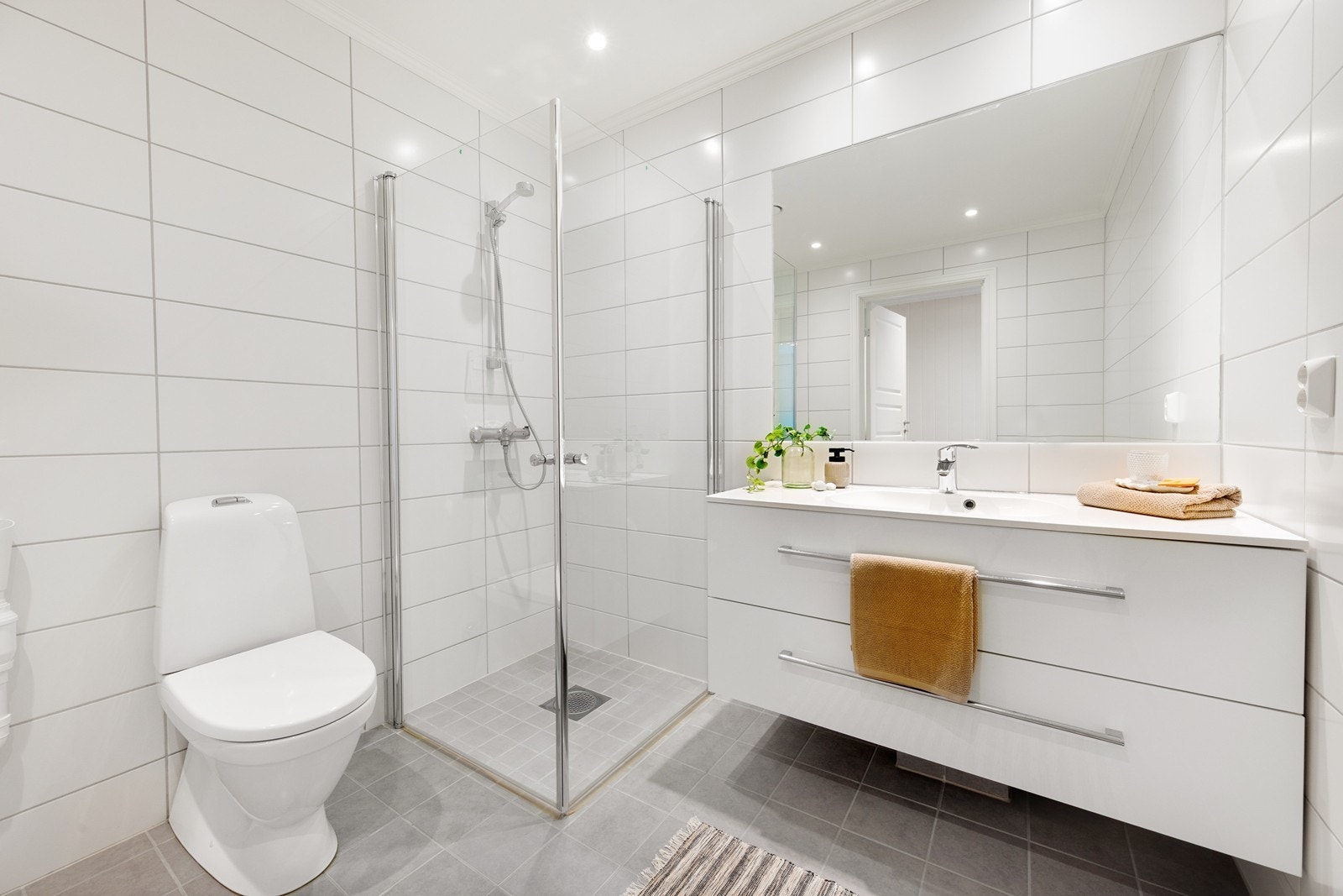 Rommet har moderne skuffeinnredning med servanttopp, toalett, dusjhjørne med innfellbare glassdører og opplegg for vaskemaskin. Galleribilde