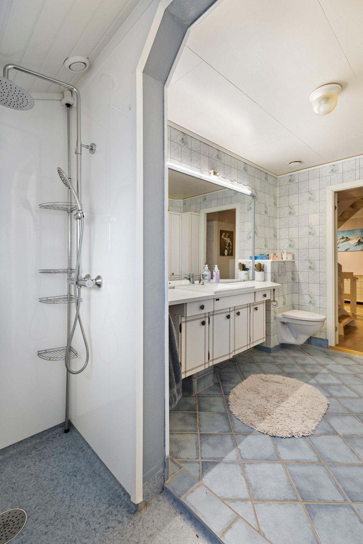 Videre er rommet utstyrt med varme i gulv, vegghengt toalett, dusj i tilbygg fra 1997, samt baderomsinnredning med servant, speil og belysning. Galleribilde