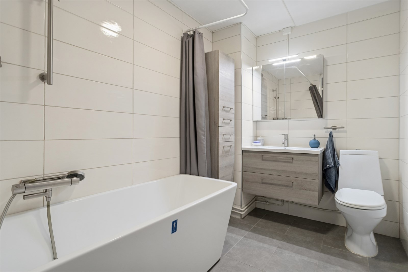 Helfliset og delikat baderom med badekar og romslig baderomsinnredning med speilskap. Galleribilde