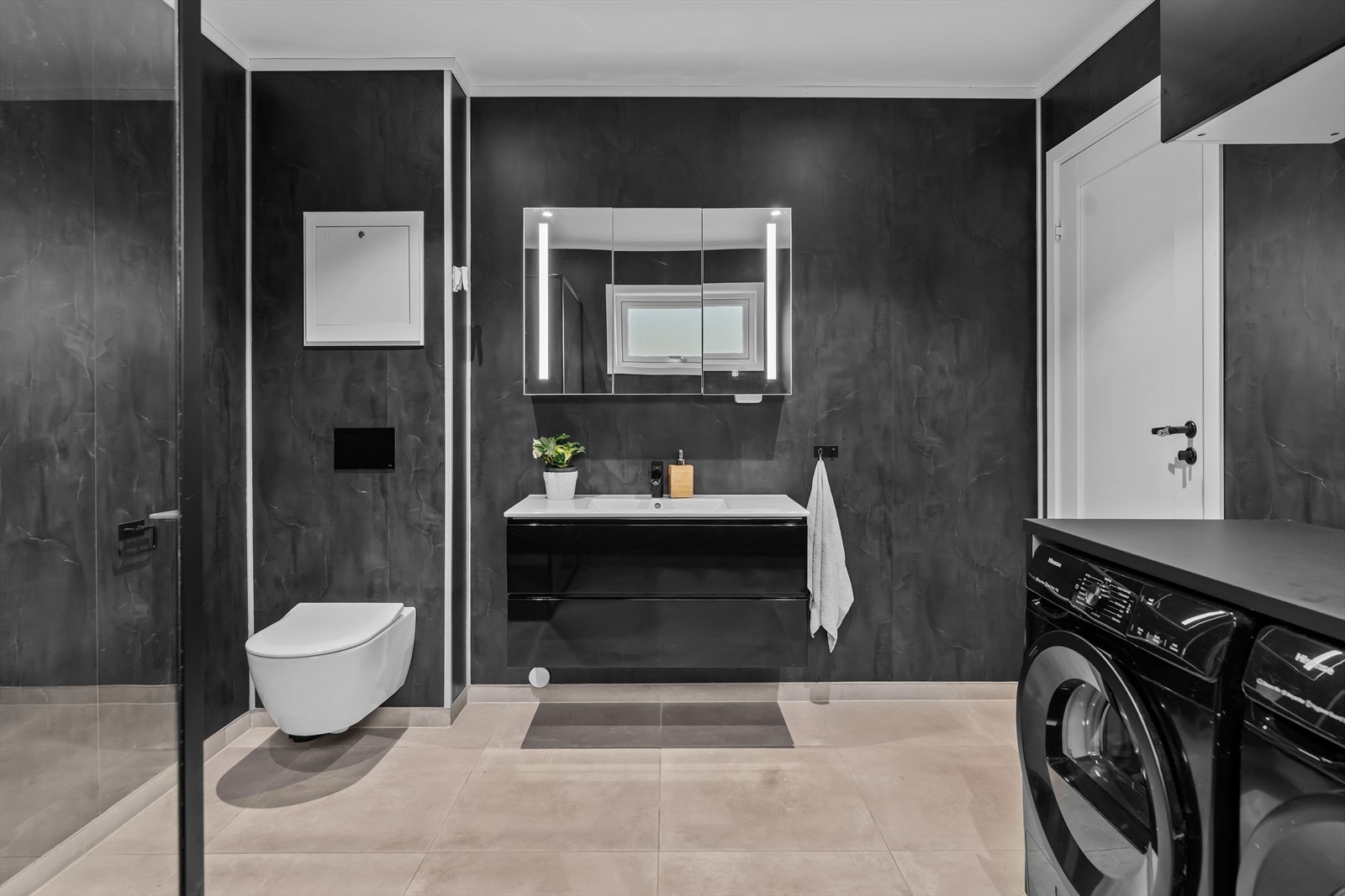 Badet har en moderne innredning med dusjhjørne med glassdører og regnfallsdusj, vegghengt toalett, servant med underskuffer samt overskap med speil og integrert belysning. Galleribilde