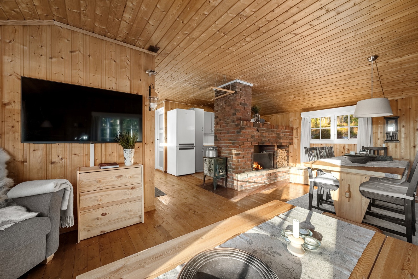 Stue med plass til både sofahjørne og spisebord. Peisovnen bidrar til ordentlig hyttekos. Galleribilde