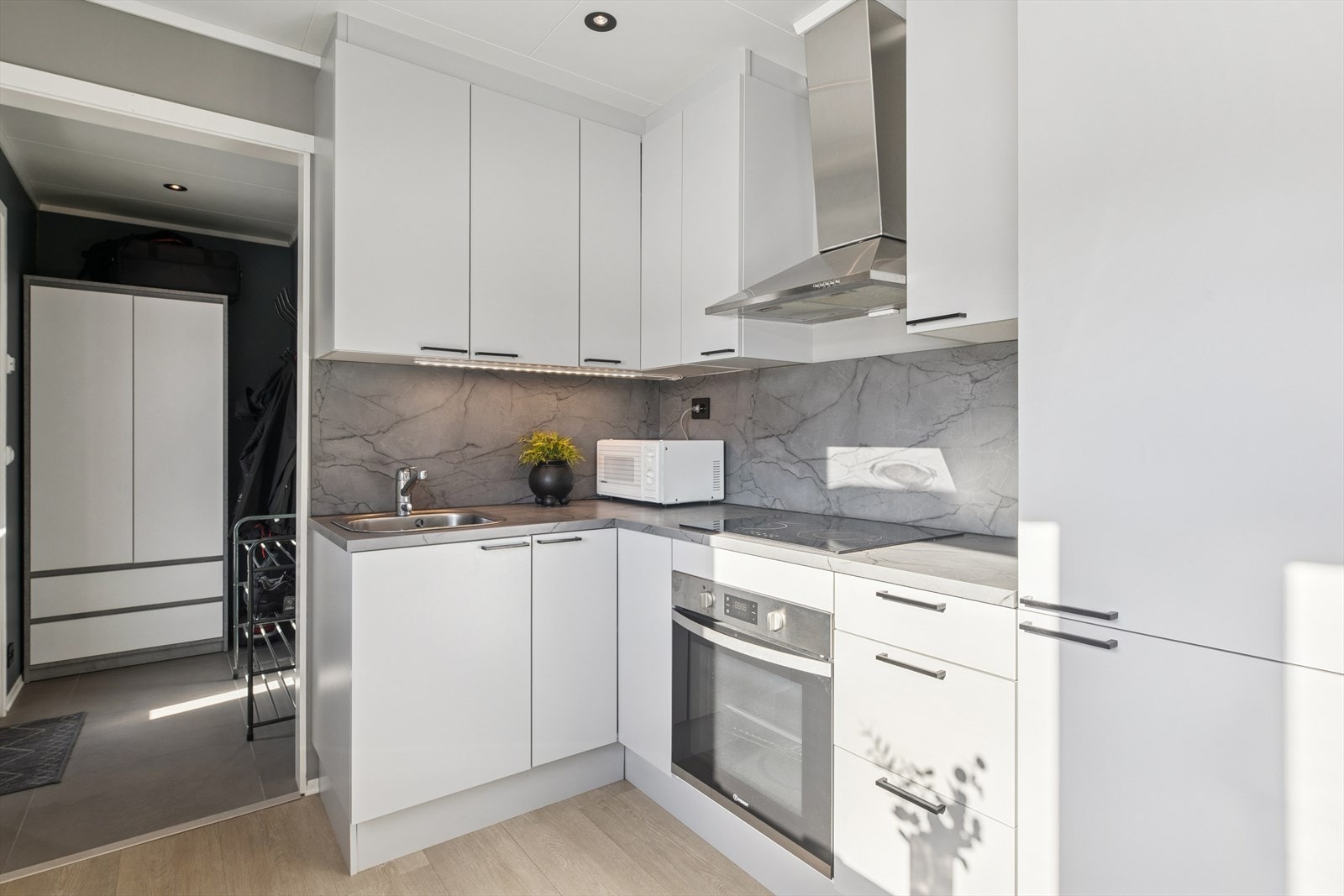 Kjøkkenet i hybelen har en innredning med glatte fronter og laminat benkeplate. Galleribilde