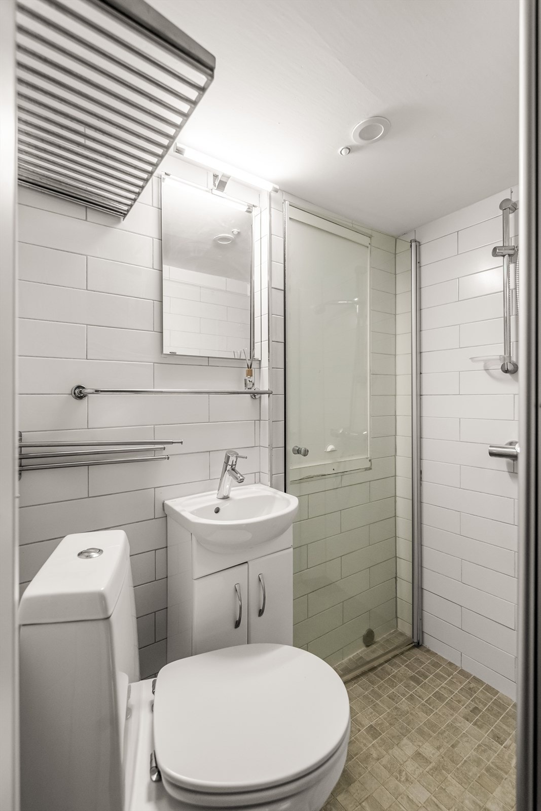 Badet i underetasjen er flislagt i lys utførelse med dusjnisje og toalett samt servant i innredning Galleribilde