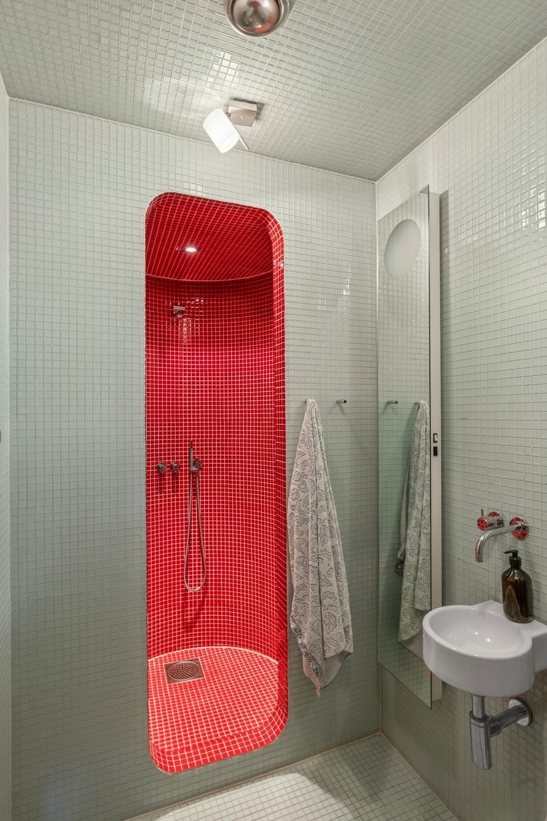 En kombinasjon av hvite og røde mosaikkfliser gir badet et moderne og friskt uttrykk, samtidig som det skaper en tydelig soneinndeling. Galleribilde