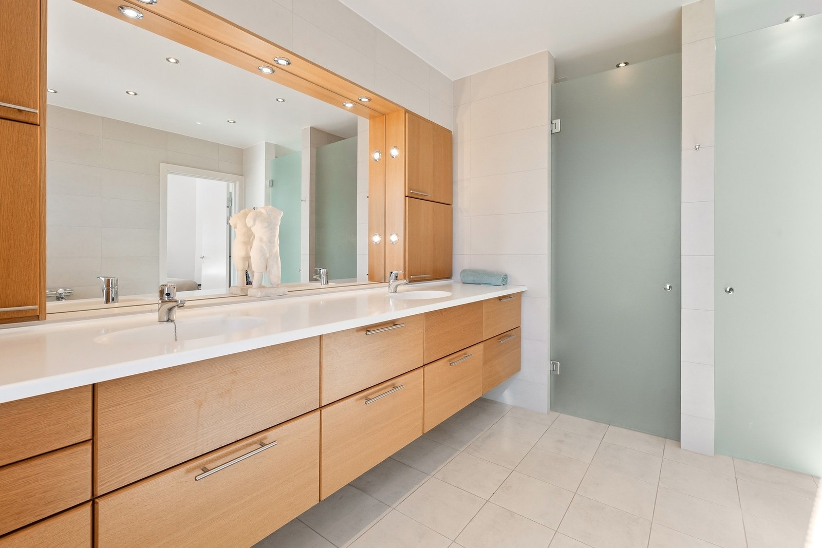 Delikat baderom tilhørende hovedsoverommet med 2 servanter, veggmontert toalett, innmurt badekar og dusjvegger/hjørne. Galleribilde