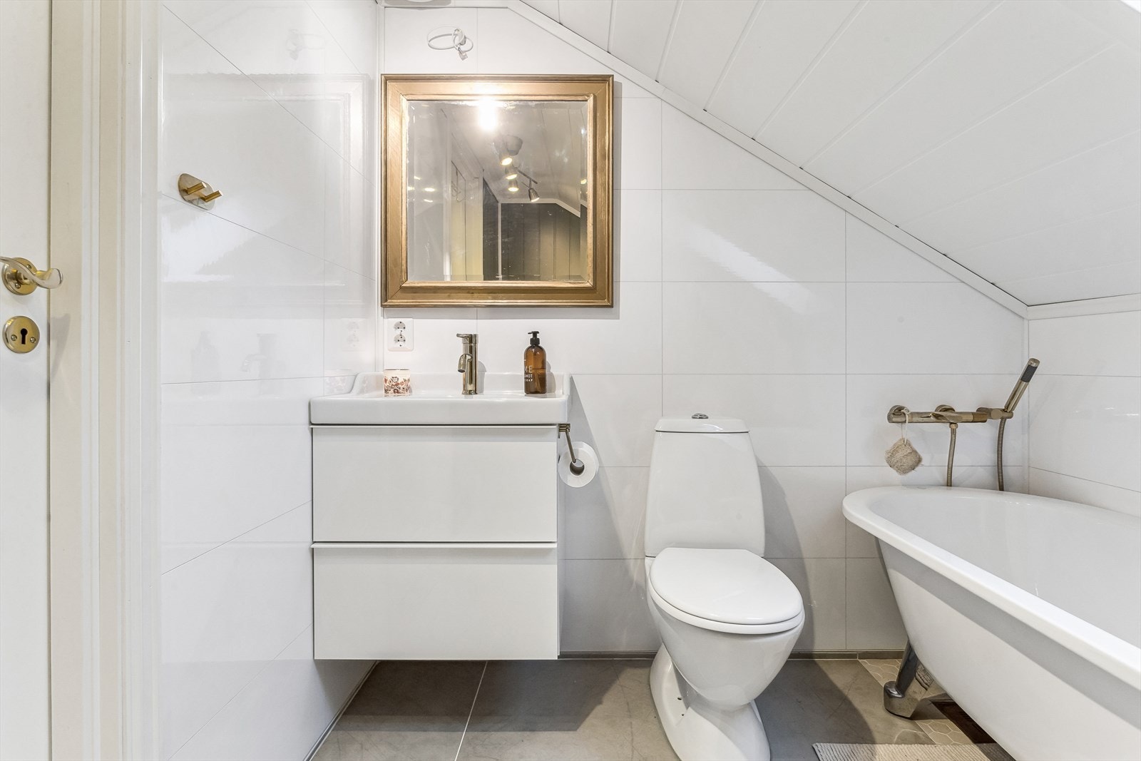 Innredet med vegghengt baderomsmøblement, gulvstående toalett og badekar Galleribilde