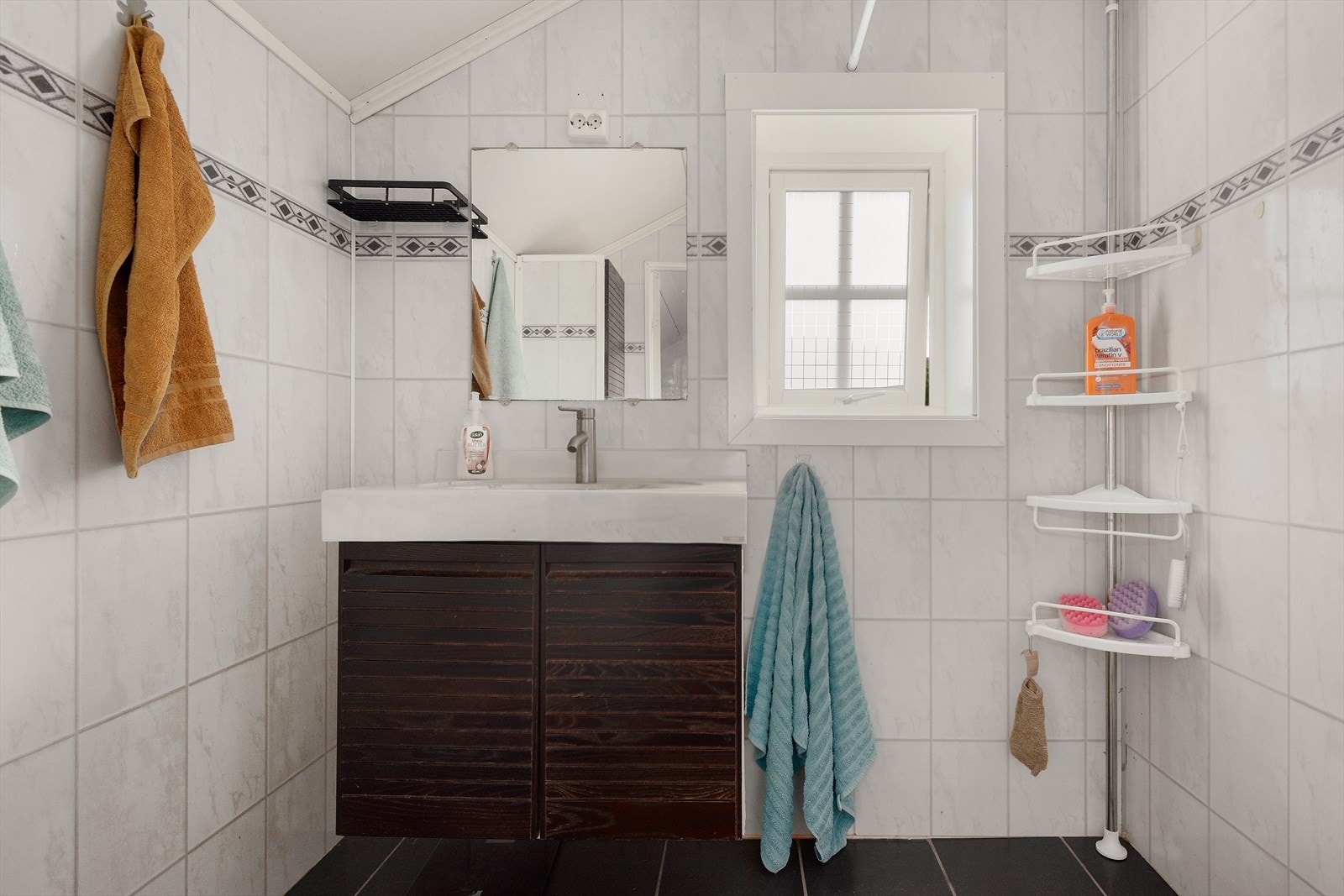 Baderom med våtromsplater på vegger og flislagt gulv med varmekabler. Rommet er innredet med servant og dusj. I tillegg til bad i denne etasjen er det et eget toalettrom. Galleribilde