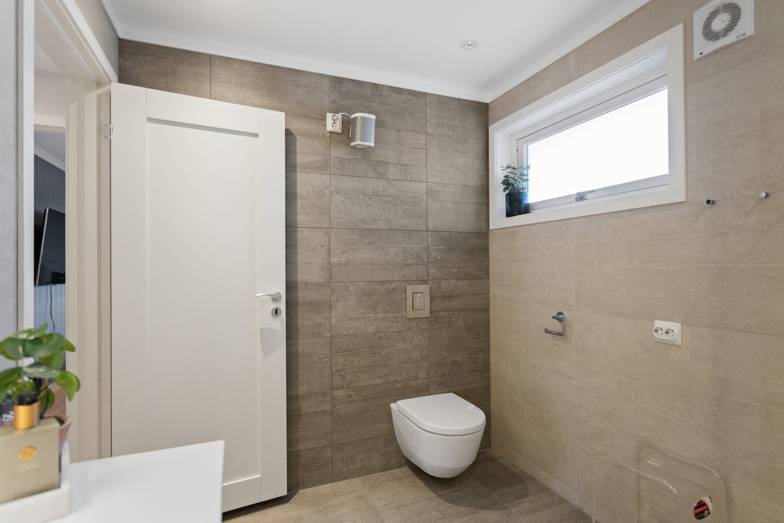 Badet har flislagt gulv og vegger, varmekabler og elektrisk vifte. Galleribilde