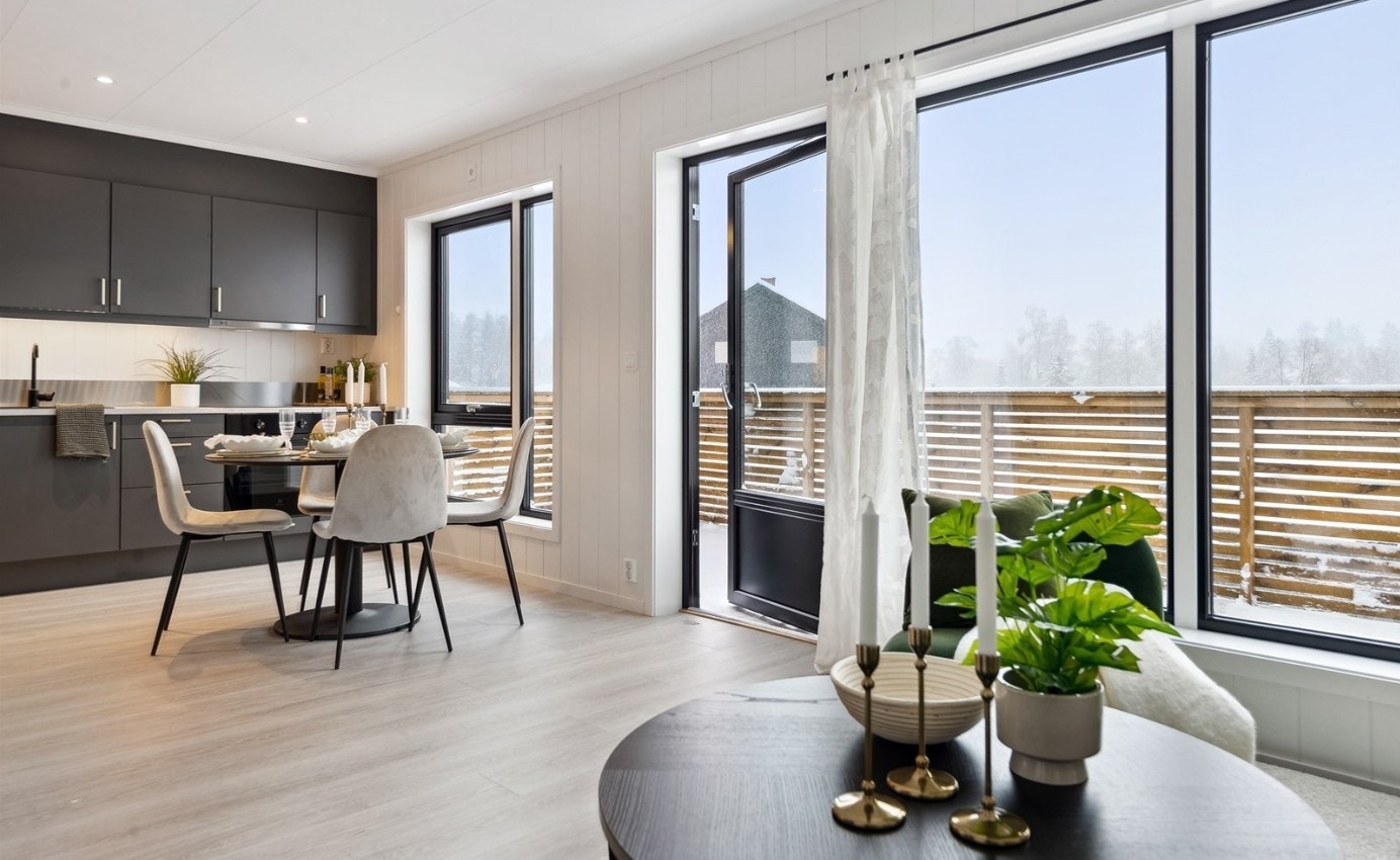 Åpen kjøkken-stueløsning med store vinduer og adkomst til verandaen. Galleribilde