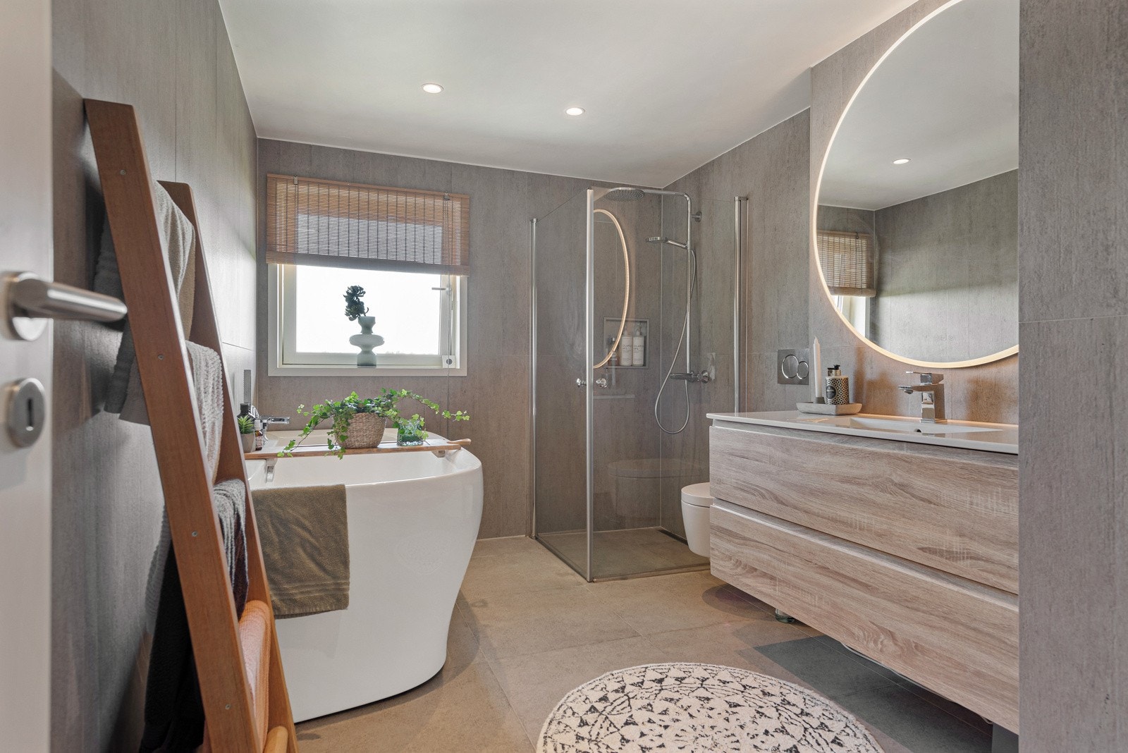 Flislagt baderom med vannbåren gulvvarme, innredet med servantskap, vegghengt toalett (Geberit), rainforest-dusj og badekar Galleribilde