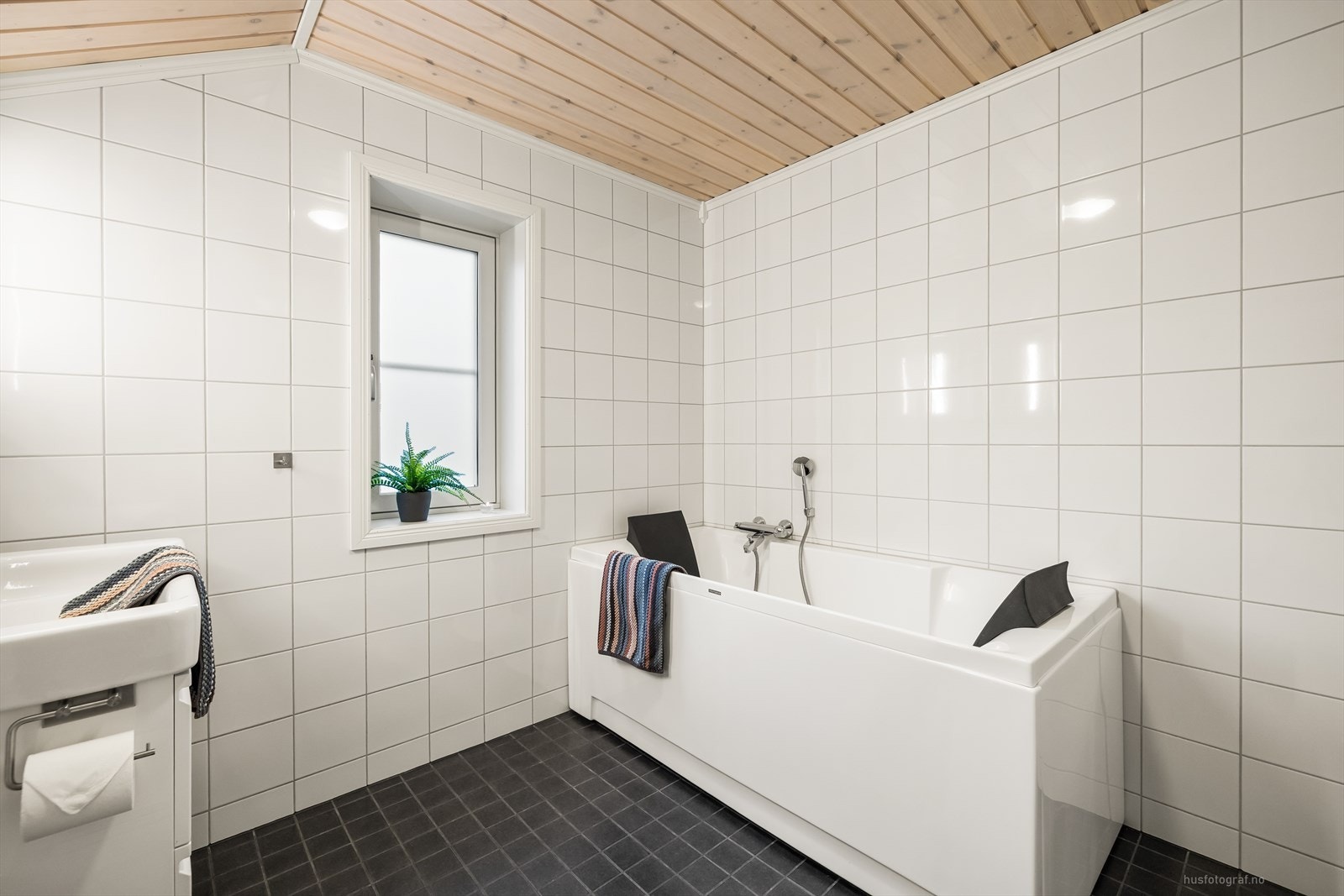 Badet er utstyrt med pen innredning og har rom for oppbevaring i skuffeseksjon, speil med belysning, toalett og badekar. Galleribilde