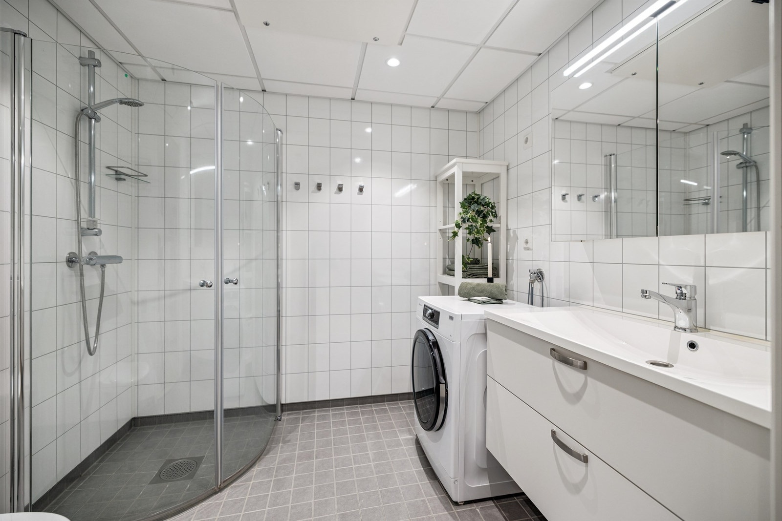 Her er det dusjhjørne med glassdører, vegghengt toalett og opplegg for vaskemaskin. Galleribilde