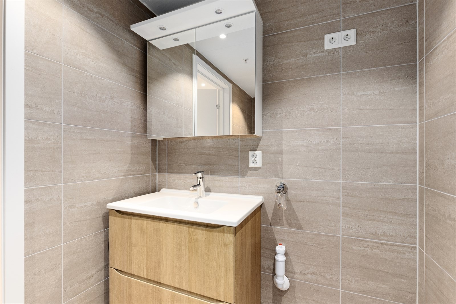 Dette badet er også utstyrt med dusjhjørne med glassvegger og eksklusiv regnfallsdusj, samt veggmontert toalett, i tillegg til opplegg for og plass til vaskemaskin. Begge bad har down-light belysning i tak. Galleribilde