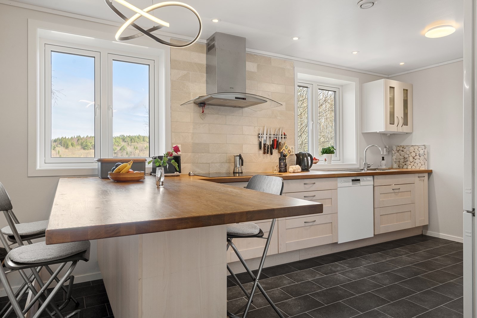 Kjøkkenet består av en funkjsonell L-form, supplert av frostede veggskap og store høyskap for praktisk lagring. Galleribilde