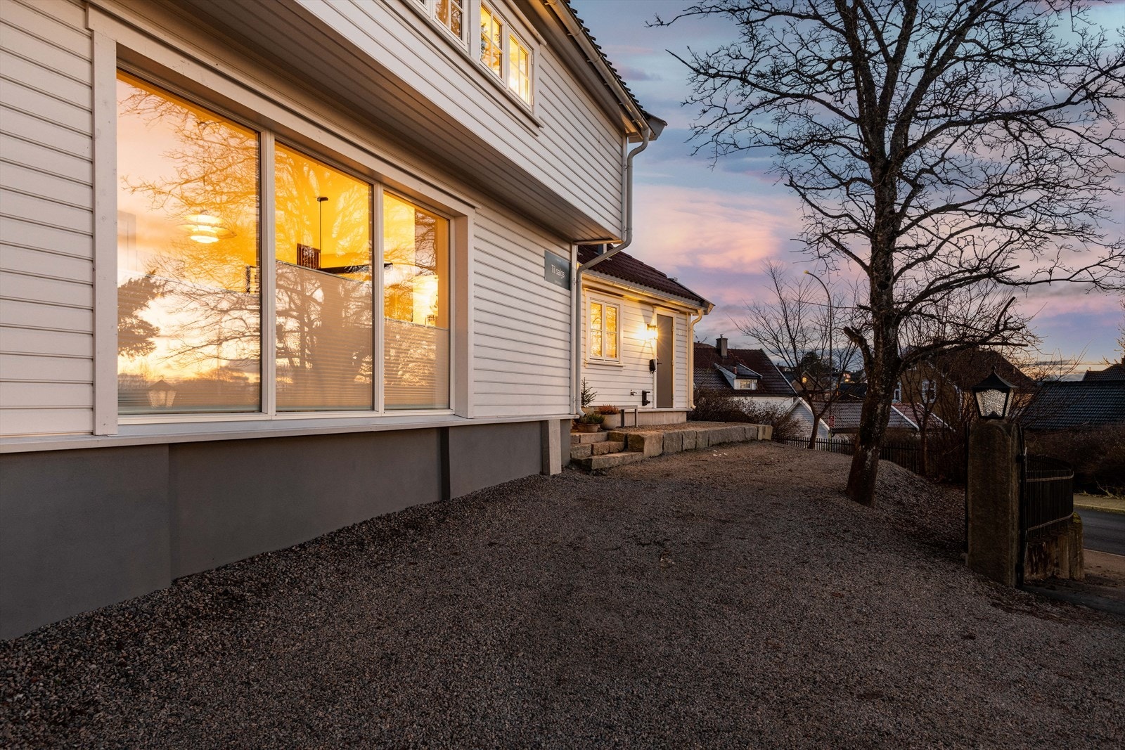 Gruset parkeringsplass, elbil-lader montert på husveggen Galleribilde