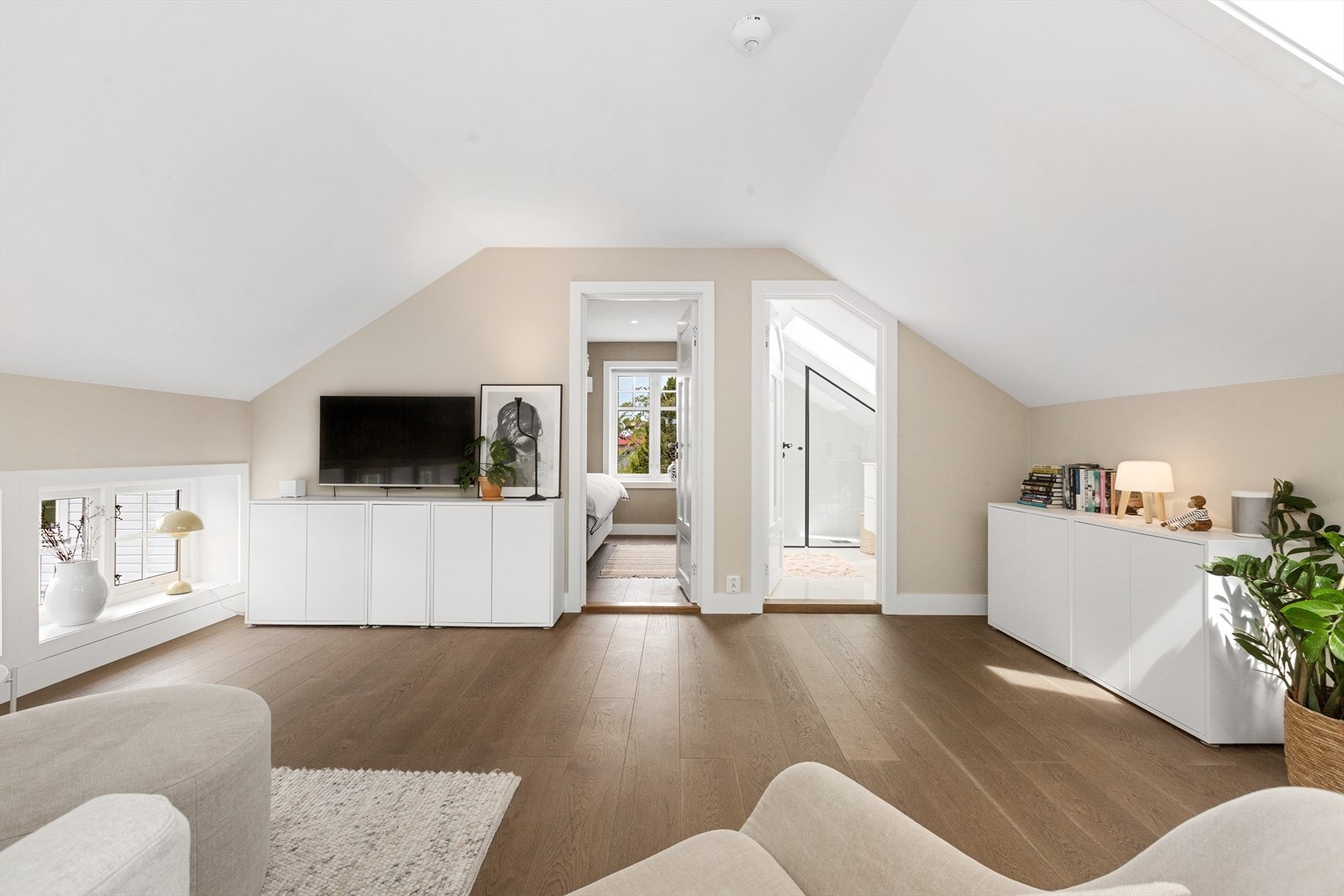 Loftstue med skråtak og god takhøyde, innredet i lyse farger og med plass til både TV-krok og sittegruppe. Galleribilde