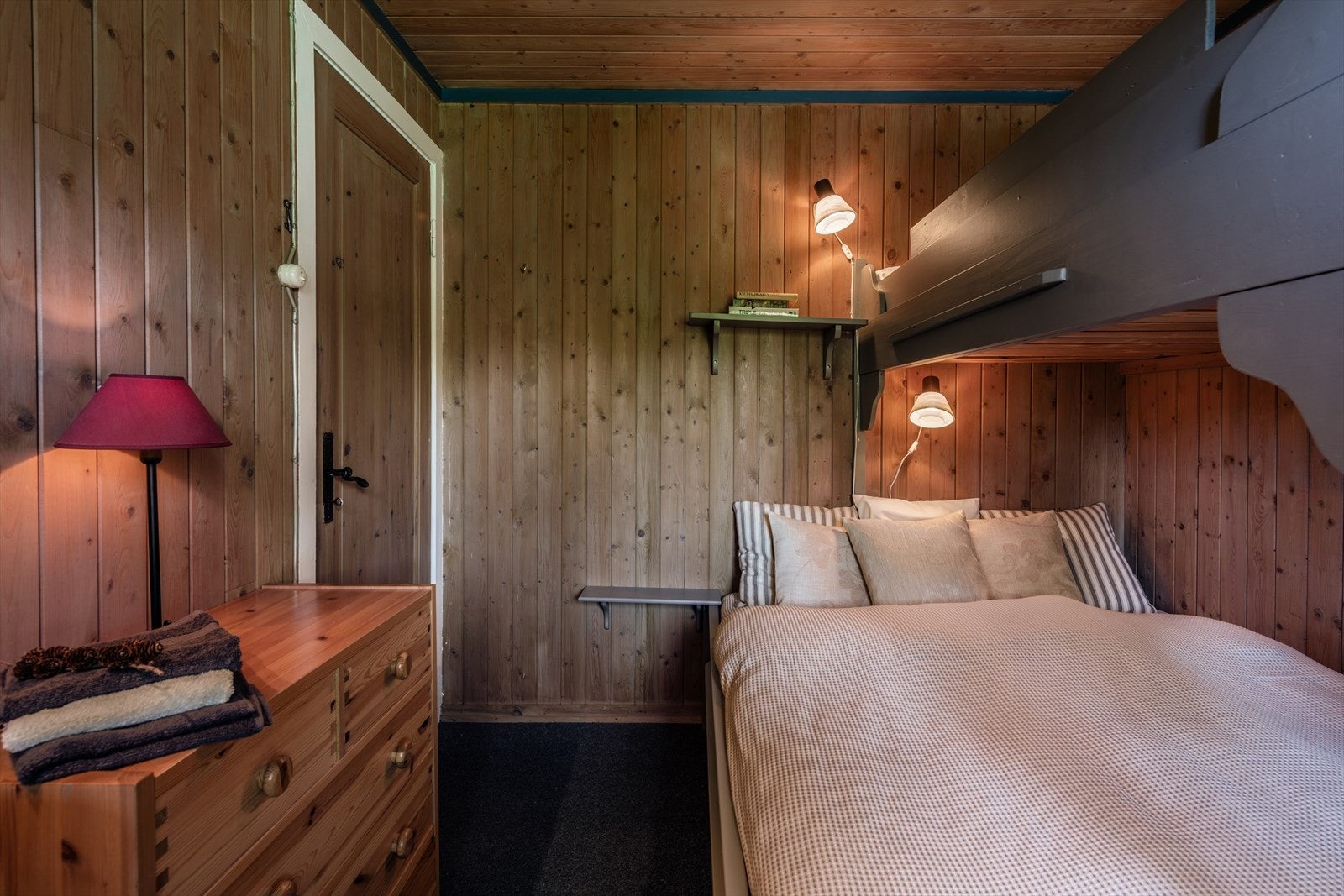 Koselig soverom med plassbygget køyeseng, trepanelvegger og varm belysning. Galleribilde