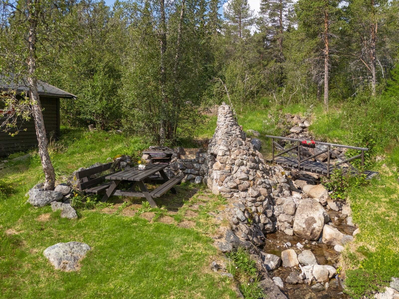 Fint opparbeidet uteområde med steinmur, bro, og benk. Perfekt for rolige stunder i naturskjønne omgivelser. Egen idyllisk bekk. Galleribilde