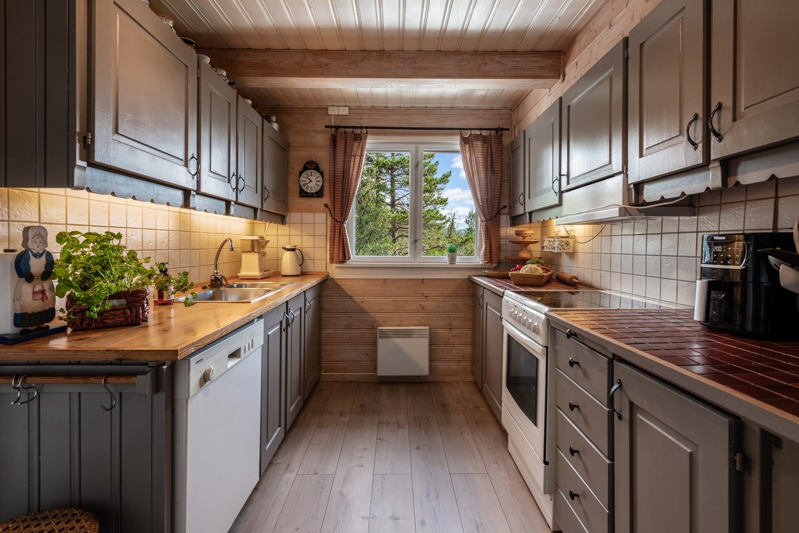 Koselig kjøkken med lys atmosfære, god benkeplass og utsikt mot naturen gjennom store vinduer. Perfekt for matlaging og hygge. Galleribilde