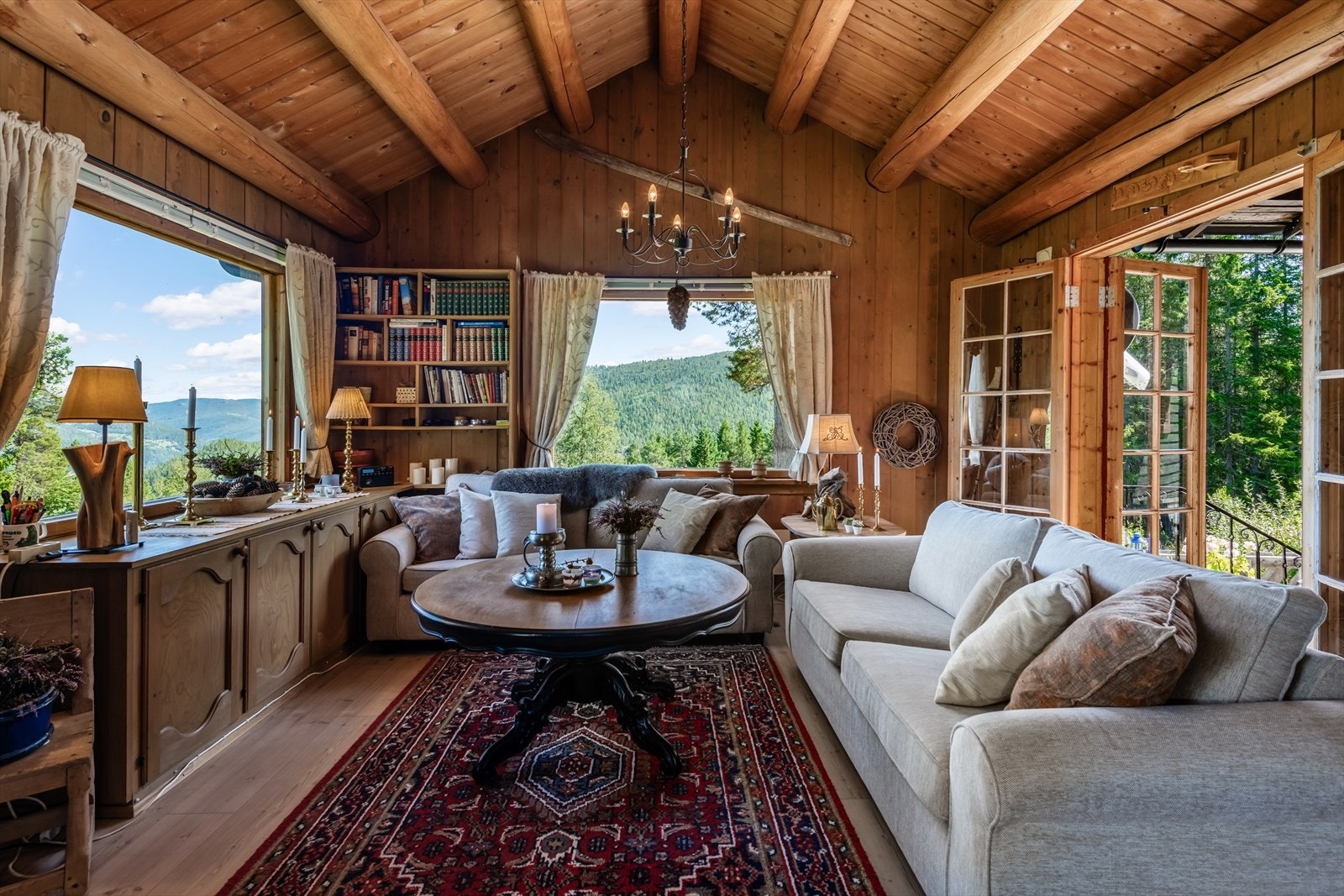 Koselig stue med store vinduer som slipper inn naturlig lys og gir en fantastisk utsikt til frodig natur. Galleribilde