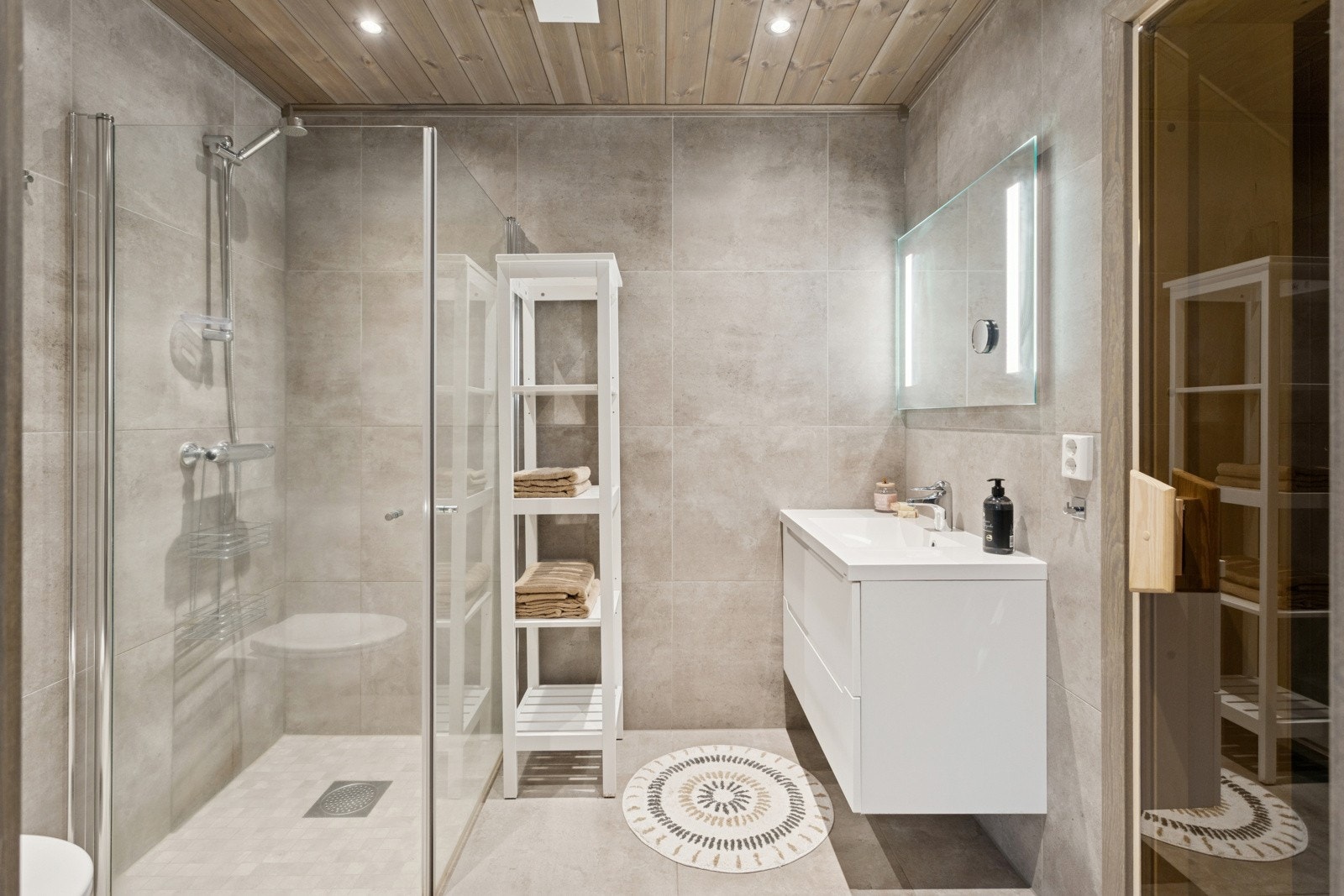 Det lekre badet har god størrelse og tilknyttet badstue. Innrendingen har heldekkende servant over underskap, samt speil med belysning over. Videre er det dusjhjørne med glassdører som kan skyves inntil vegg, samt toalett. Galleribilde