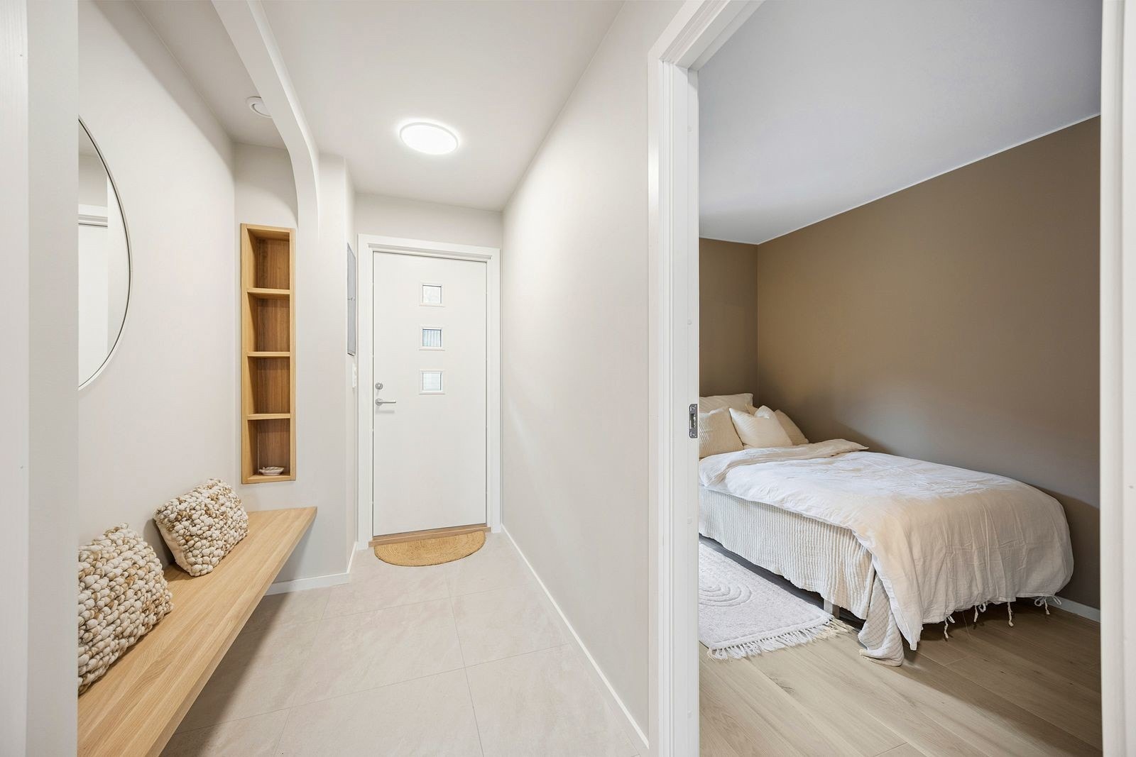 Lekre snekkerbyggede løsninger også i entre, med en praktisk sittebenk og innebyggede hyller. De lyse flisene på gulvet er både elegante og funksjonelle. Galleribilde