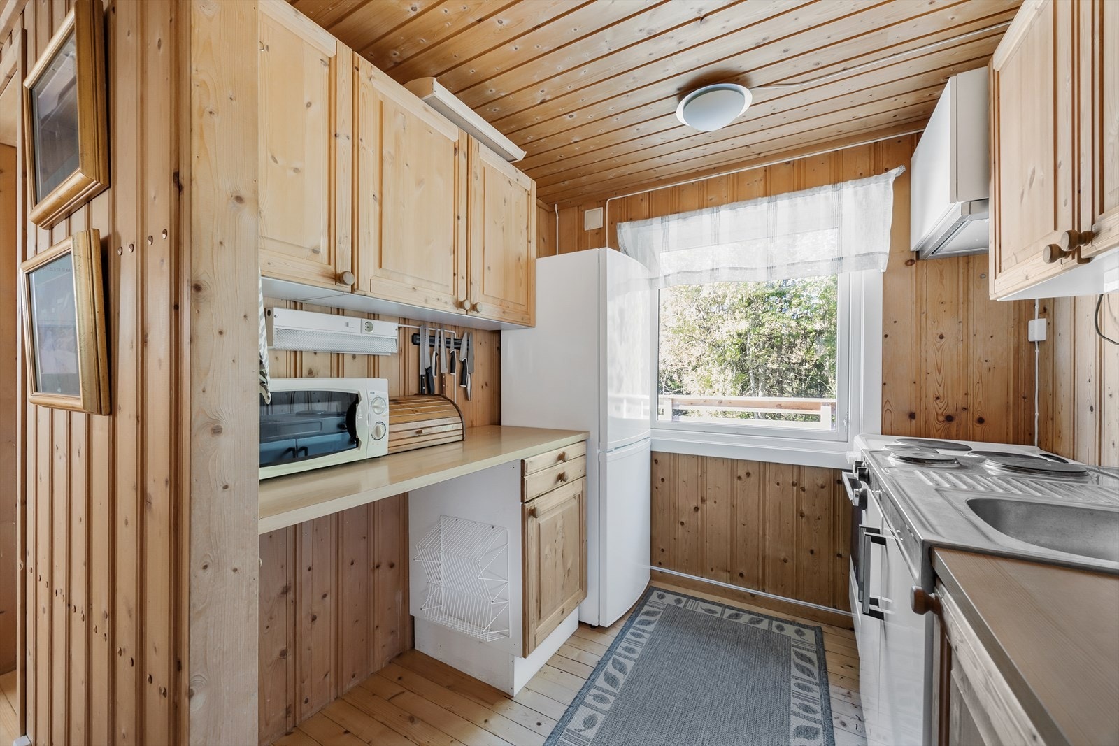 Separat og funksjonelt kjøkken med fronter av furu og lys benkeplate i laminat. Galleribilde