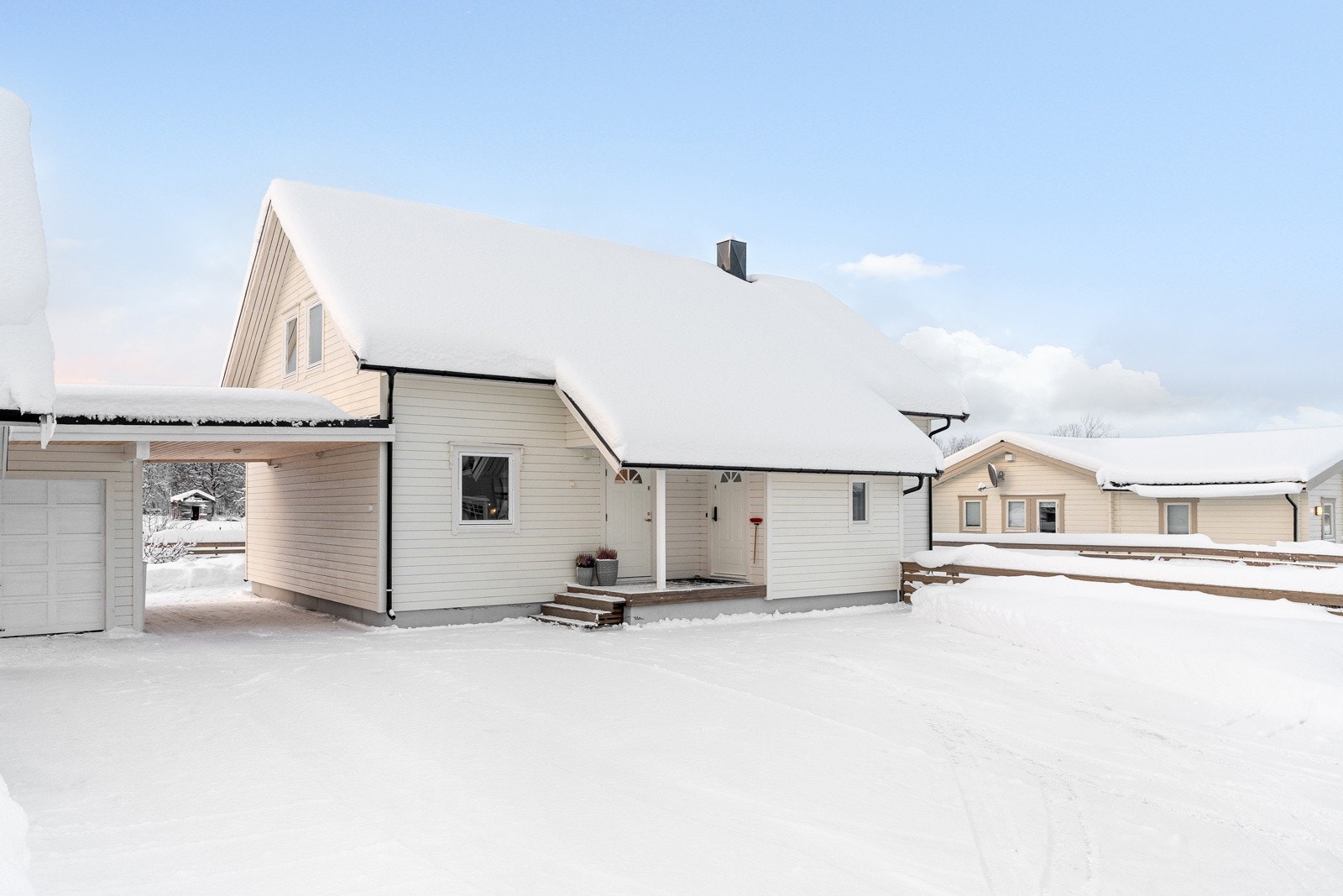 Asfaltert gårdsplass og takoverbygd inngangsparti.