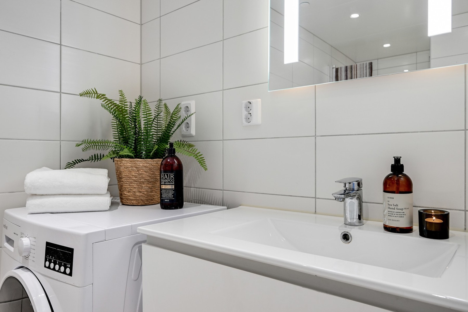 Badet inneholder servant med skuffer, speil med lys, veggmontert wc og dusjhjørne Galleribilde