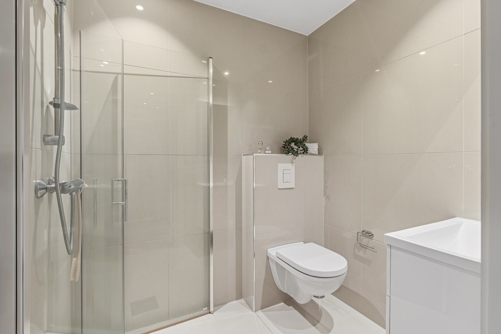 Pent helfliset badeværelse med dusjhjørne, servant og vegghengt toalett Galleribilde