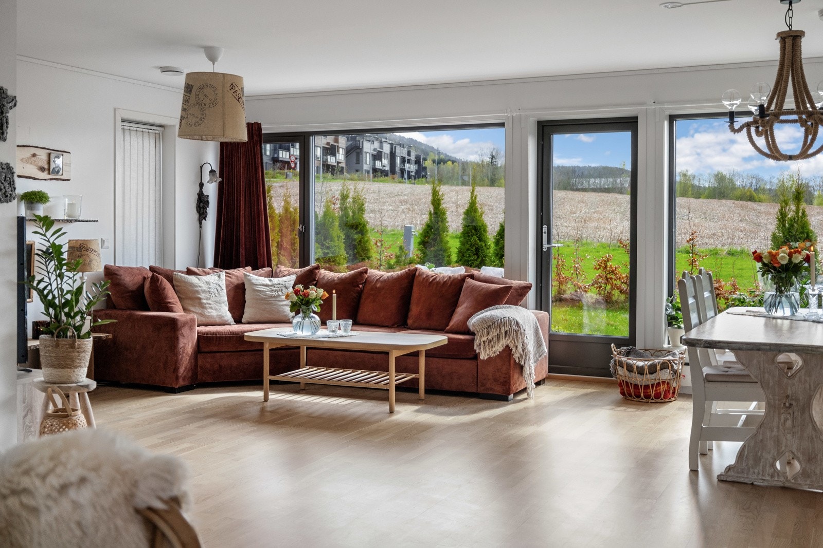 Romslig stue med store vinduer og utsikt mot grøntområde. Lys parkett og god plass til sofa og spisebord. Galleribilde