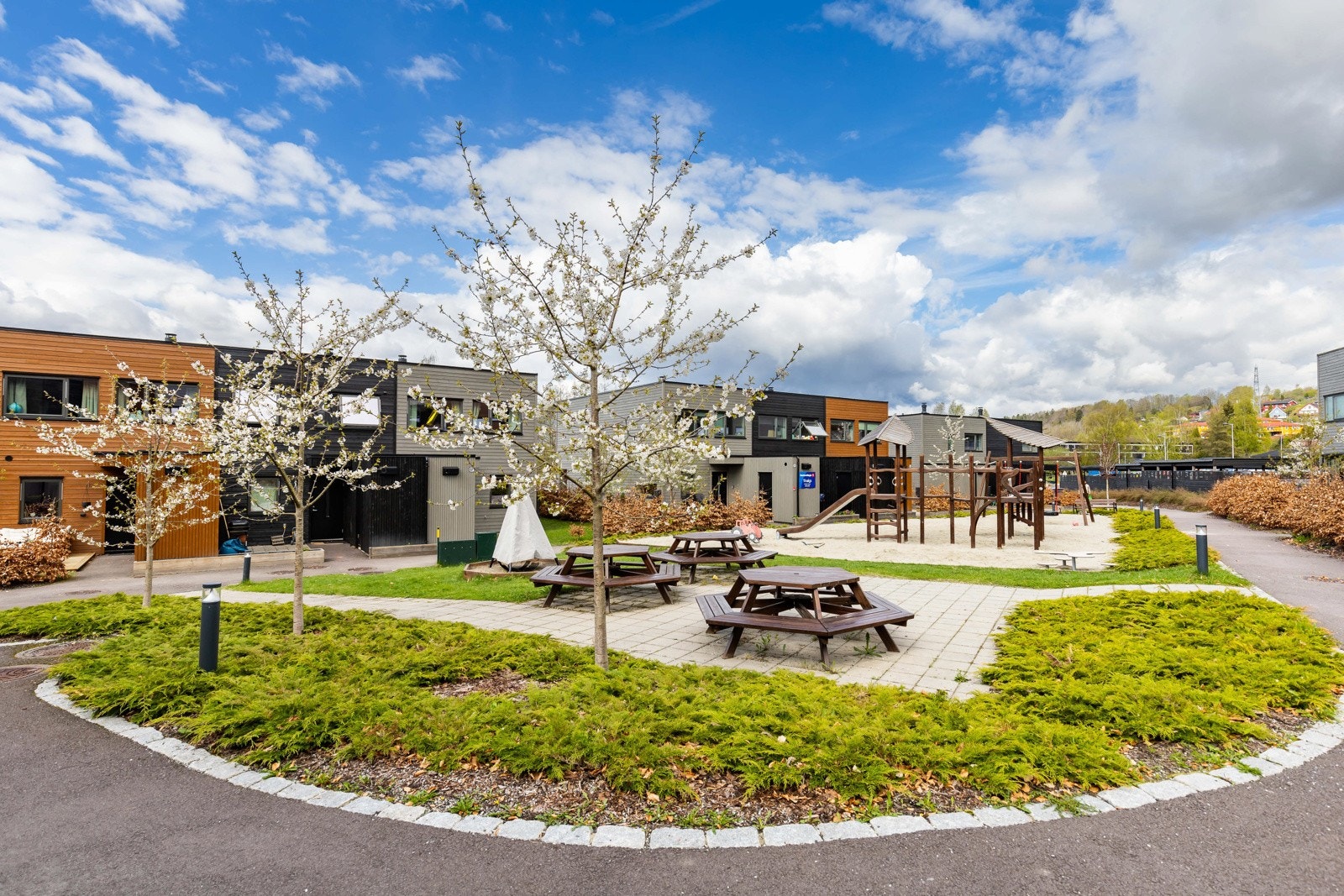 Moderne rekkehus med felles lekeplass og sitteområder i et pent opparbeidet uteområde. Galleribilde