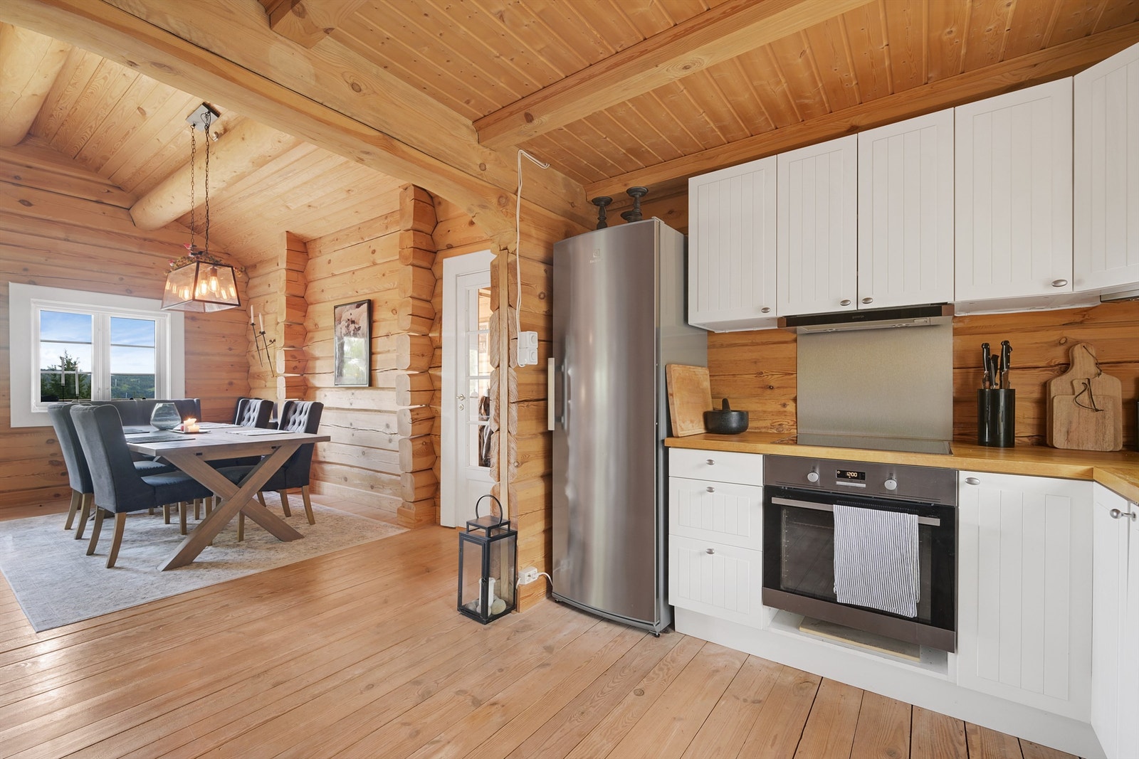 Koselig kjøkken med profilerte fronter, heltre benkeplate og integrerte hvitevarer som oppvaskmaskin, platetopp og stekeovn. Galleribilde