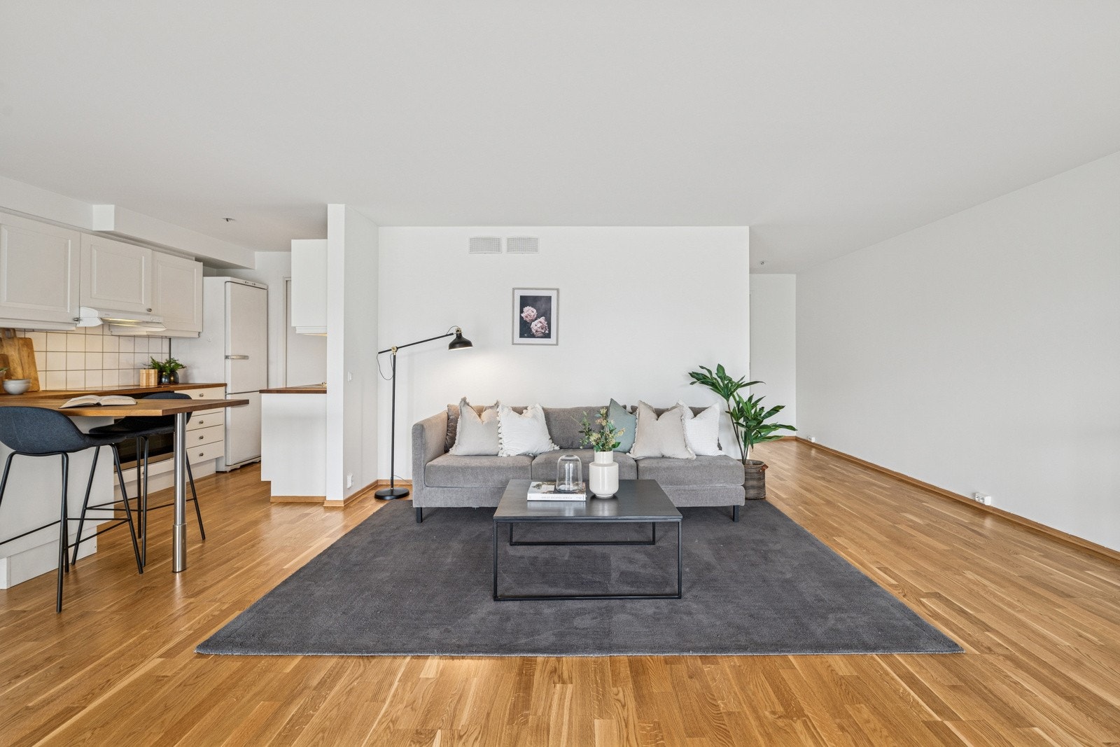 Lys og romslig stue med åpen kjøkkenløsning og god plass til både sofagruppe og spiseplass - et naturlig samlingspunkt i boligen. Galleribilde