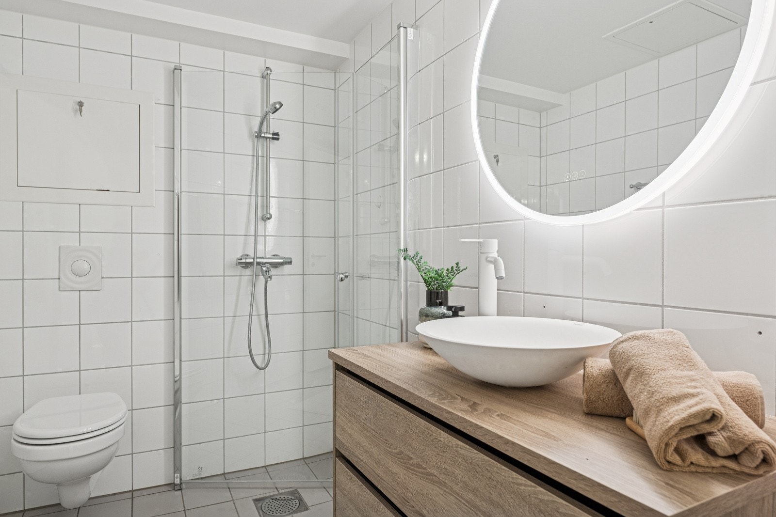 Moderne bad med stilren innredning, vegghengt toalett og romslig dusj med glassdører. Galleribilde