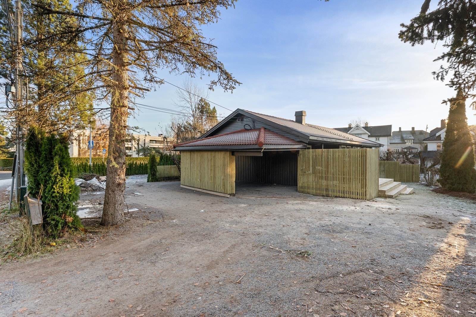 Boligen har parkering i carport med elbillader og 2 parkeringsplasser på gårdsplass (til høyre i bildet). Galleribilde