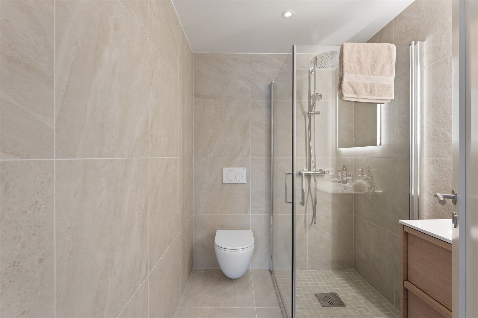 Bad 2 fra 2025 med adkomst fra gang. Romslig dusjsone med regn- og hånddusj, og dører i herdet glass. Flislagt gulv med varmekabler. Galleribilde