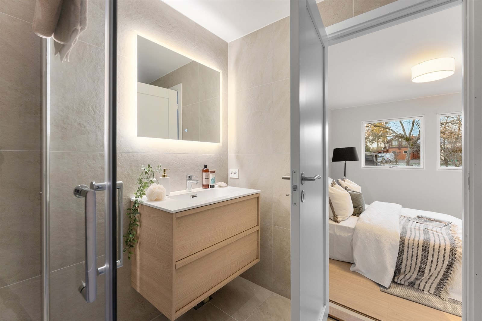 Bad en- suite med dusjhjørne med dører i herdet glass og fliser i delikate farger. Galleribilde