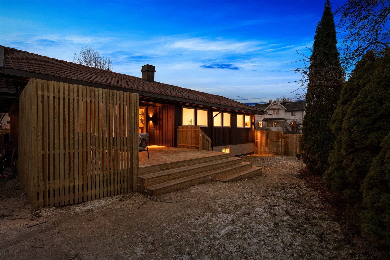 Terrassen og hagen omkranses av spilevegger og trær som gir privatliv. Galleribilde