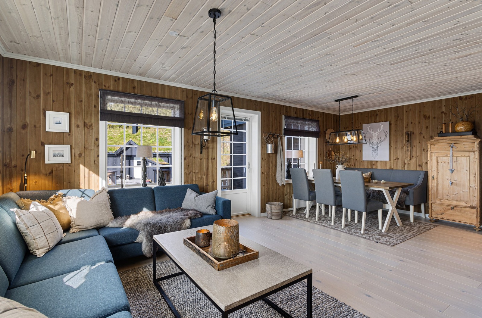 Åpen stue/kjøkkenløsning med beisede panelvegger og parkett på gulv Galleribilde