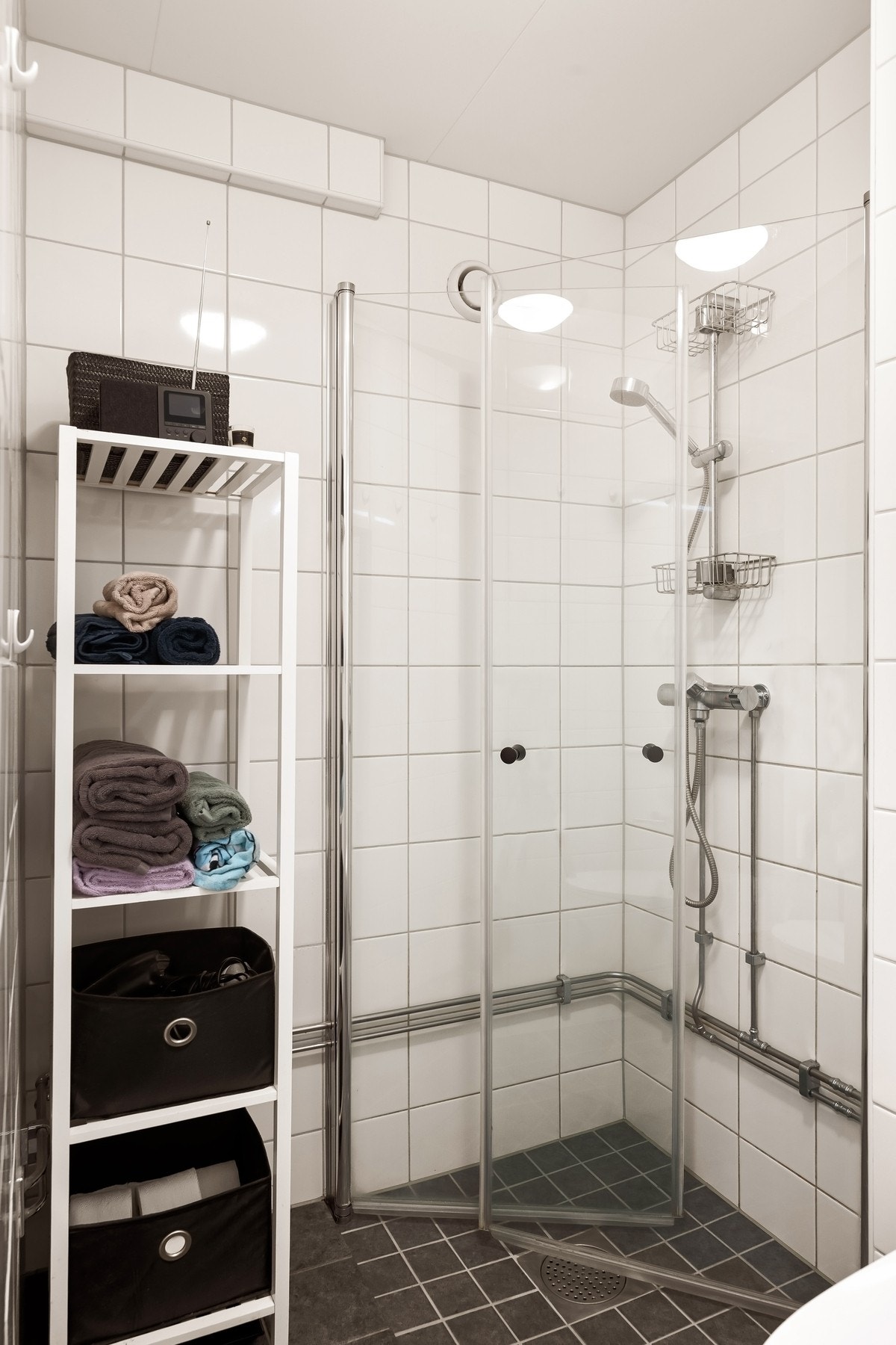 Nedsenket dusjnisje med glassdører, vegghengt toalett og moderne innredning med skuff og nedfelt vask. Galleribilde