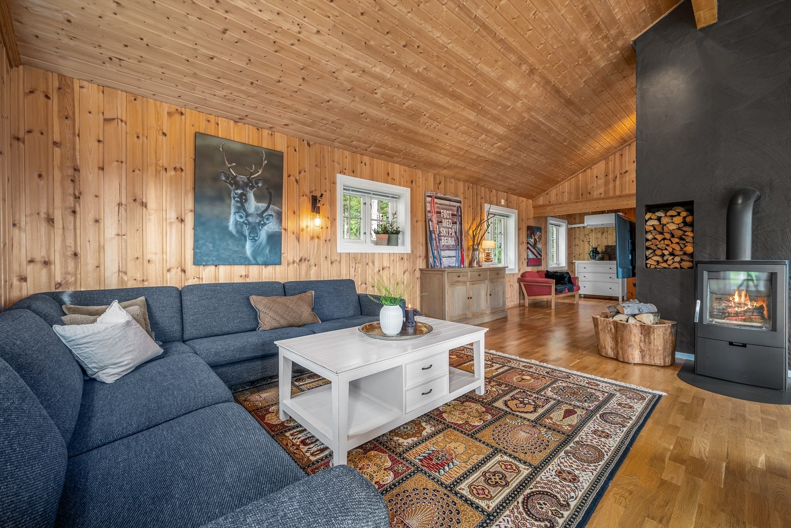 Stuen er et nydelig rom med panelkledde overflater, høy, skrånende himling og koselig peisovn. Galleribilde