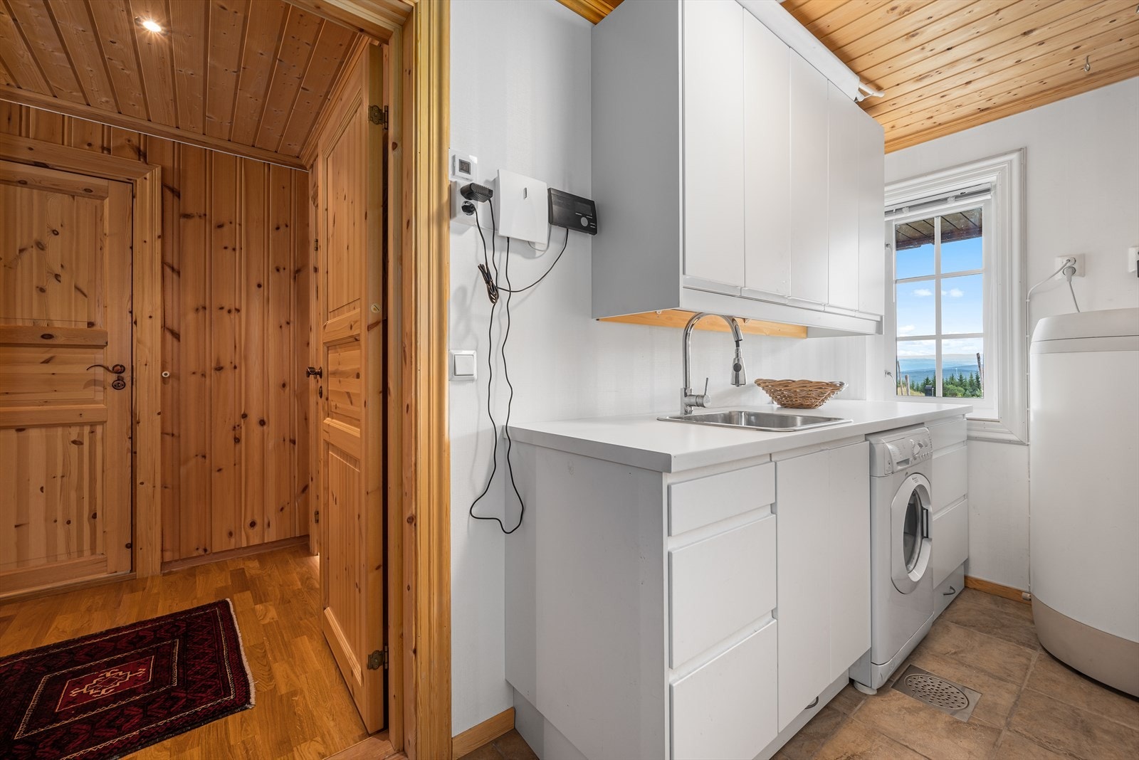 Hytta har praktisk vaskerom med stor, hvit innredning, nisje for vaskemaskin og bereder på 200 liter. Galleribilde