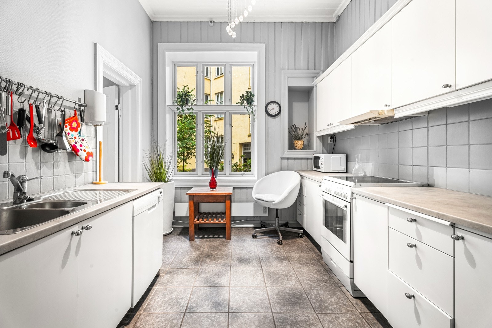 Hybelkjøkken med slette fronter, overskap med benkebelysning og fliser på vegg. Laminat benkeplate med nedfelt dobbel stålkum og ett-greps armatur i krom Galleribilde